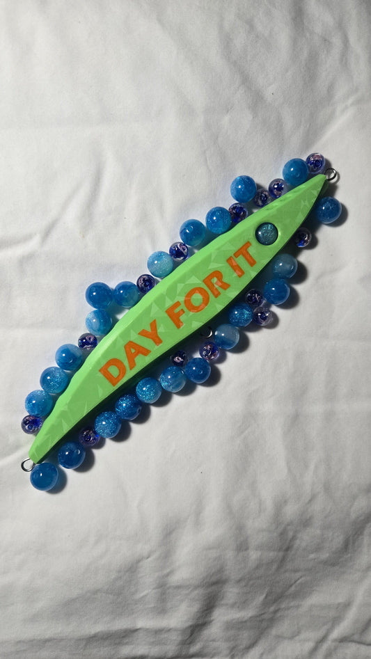 Fishing stickbait lure by trevs lures embossed with day for it with eyeballs around it.